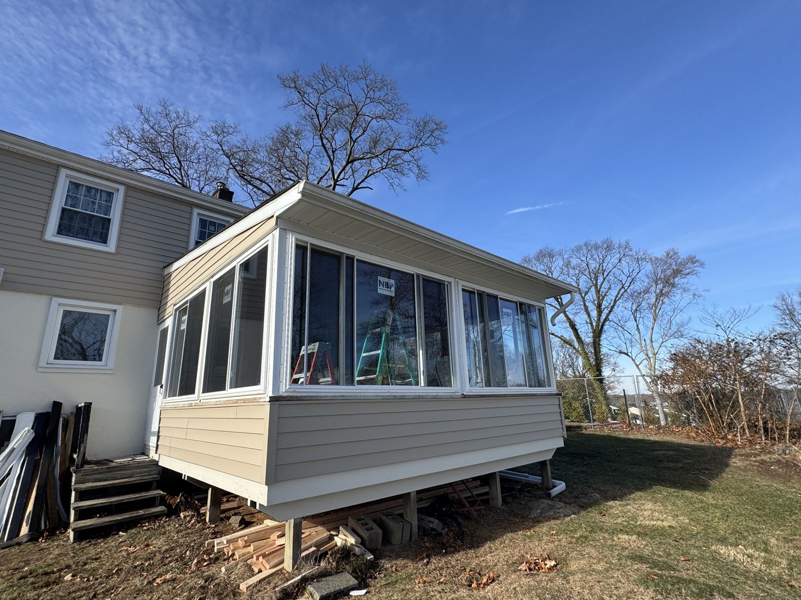 The same porch enclosed as a sunroom with new windows, siding and trim