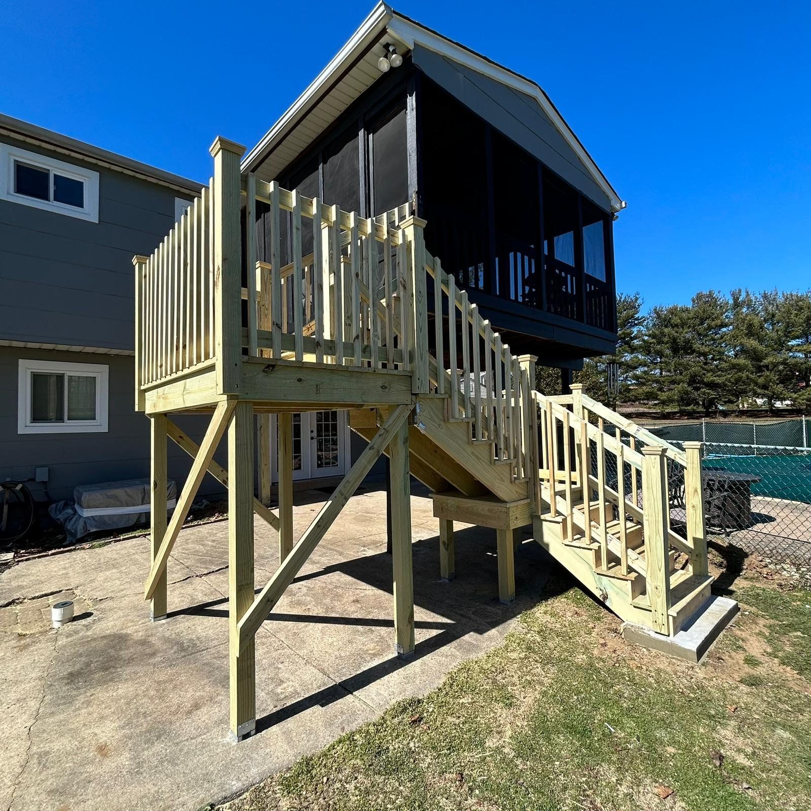 New pressure-treated stairs with a landing, braced posts on steel bases and full railings up to the screened porch