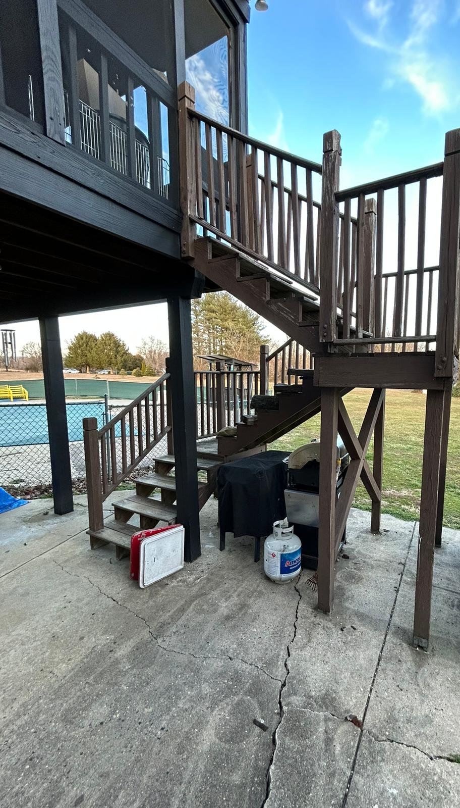 Old weathered wood stairs and landing up to a second-floor screened porch, before replacement